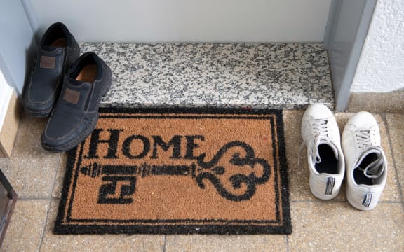 27 May 2019, Hessen, Frankfurt/Main: Two pairs of shoes stand next to a doormat with the inscription "Home". The installation of modular living elements on the upper floors of existing buildings is intended to create more living space in Frankfurt. (Too much focus from 27.05.2019) Photo: Boris Roessler/dpa (Photo by BORIS ROESSLER / DPA / dpa Picture-Alliance via AFP)