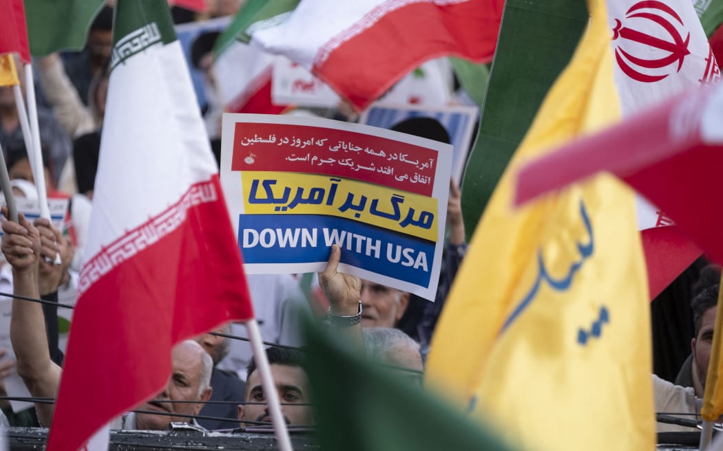 An Iranian man holds an anti-US placard while celebrating the ceasefire, which they believe is a victory over Israel in a 12-day war, during a rally in downtown Tehran, Iran, on 24 June, 2025. Iran and Israel agree to a ceasefire after a 12-day war, proposed by US President Donald Trump and mediated by Qatar.