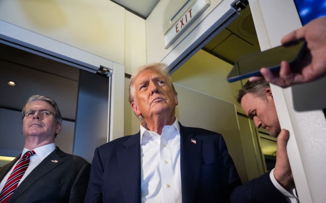 US Treasury Secretary Scott Bessent, left, US President Donald Trump and US Trade Representative Jamieson Greer, right, take questions from reporters aboard Air Force One as they fly to Japan on 27 October, 2025.