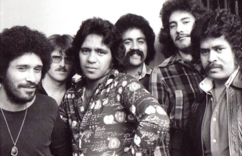 Collision are a band of men with big hair and patterened shirts.