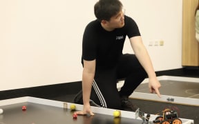 Kevin Guo points to small robot.