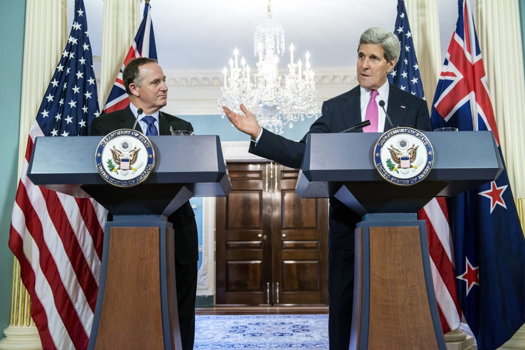 John Key listens as John Kerry speaks to the press after a meeting at the State Department.