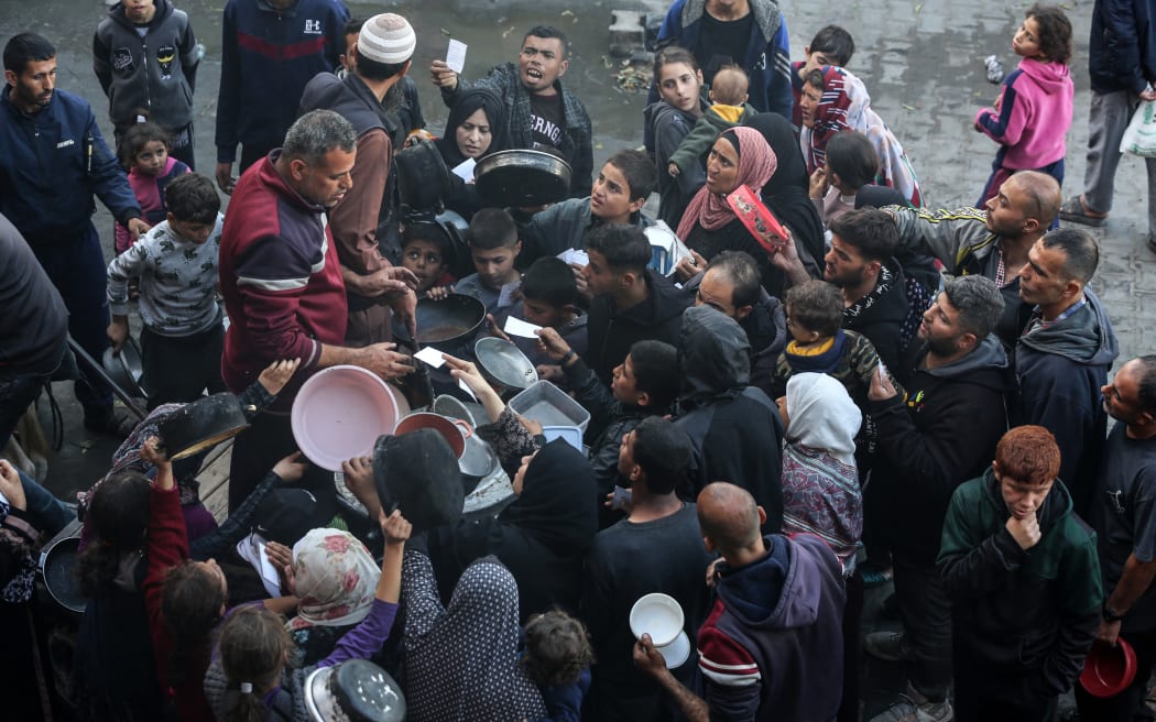 Palestinians are waiting to collect food at a donation point in a school that is sheltering Palestinians displaced by the conflict in Gaza between Israel and the Palestinian Hamas movement in Deir El-Balah, in the central Gaza Strip, on December 24, 2023, as battles continue between Israel and the militant group Hamas.