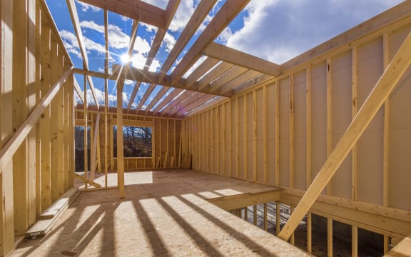 The frame of a new house under construction, with a blue sky behind it (file)