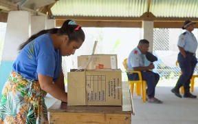 This frame grab from AFPTV video footage shows a woman filling-in her ballot at a polling station before voting in Kiribati's national elections in Tarawa on August 14, 2024. Polls closed in the Pacific nation of Kiribati on August 14, capping a campaign dominated by cost of living worries, rising sea levels and questions about the benefit of deeper ties with China. (Photo by Raimon Kataotao / AFPTV / AFP)