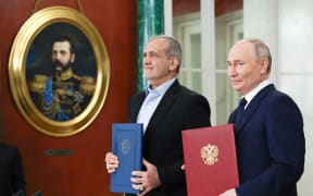 In this pool photograph distributed by the Russian state agency Sputnik, Russia's President Vladimir Putin and Iranian President Masoud Pezeshkian sign a strategic partnership treaty during a ceremony following their talks at the Kremlin in Moscow on January 17, 2025.