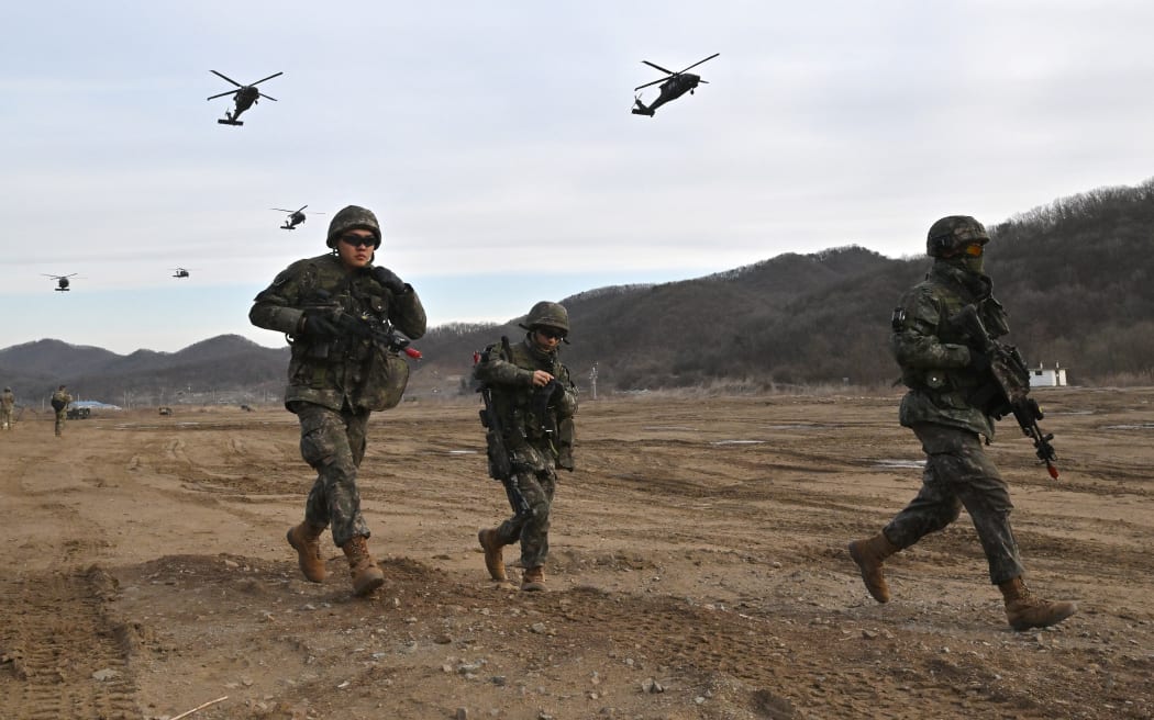 South Korean soldiers move to a position as US Army UH-60 Black Hawk helicopters fly overhead during a joint South Korea-US drill at a military training field in the border city of Paju on 16 March, 2023, as part of the Freedom Shield joint military exercise.