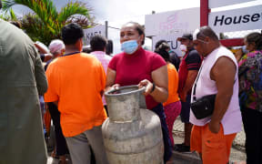 A woman carries a refilled gas container in the centre of the capital Nuku'alofa ahead of the country's first lockdown on February 2, 2022