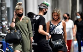 People wear protective face masks as they walk in the city center of Antwerp, Belgium, on July 27, 2020.