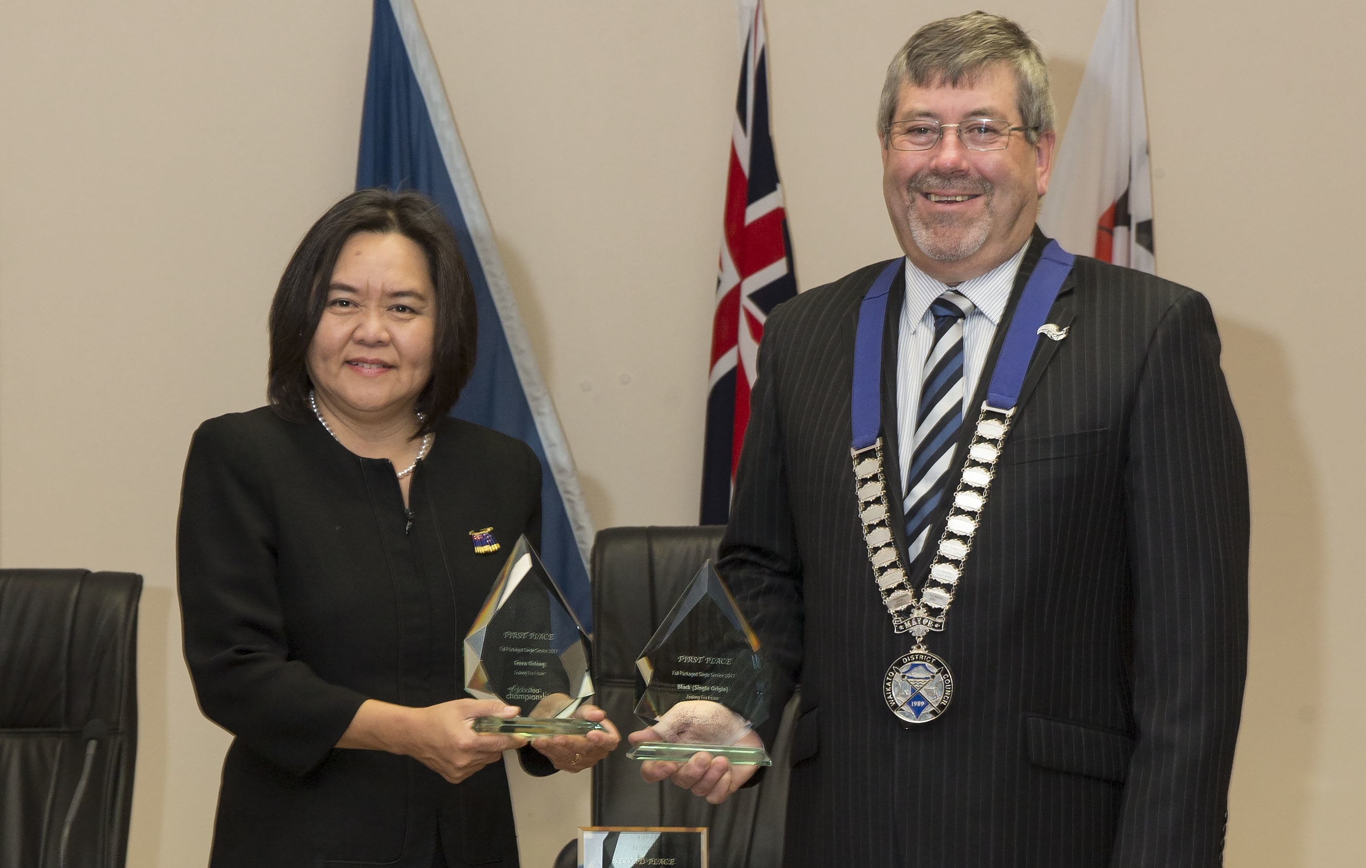 Gigi Crawford of Zealong Tea Estate and Mayor Allan Sanson of Waikato District Council, with the three trophies won by Zealong Tea Estate