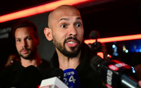 Andrew Tate (R) and his brother Tristan (L) speak to the media as they arrive in Romania back from US, in Bucharest March 22, 2025. Self-described misogynist influencer Andrew Tate return to Romania, where he is facing rape and human trafficking charges, after a trip to the US. The British-American figurehead of the online masculinist movement travelled to Florida, together with his brother, last month, marking the first time he had been out of the eastern European country since his 2022 arrest. Under judicial supervision, the Tates need to report to authorities on March 24, a no-show potentially leading to "preventive arrest", according to Romanian authorities. (Photo by Daniel MIHAILESCU / AFP)