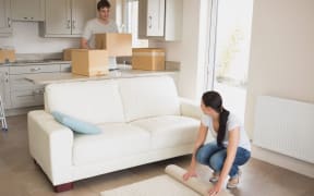 16053421 - two young people moving into their house and furnishing the living room