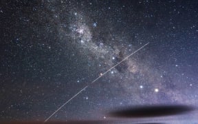 a photo of a night sky, with a streak of light across it