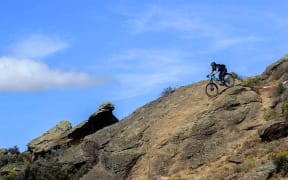 Bike and rider starting descent of rocky outcrop