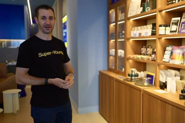 Super Young co-founder Tristan Sternson stands near shelves with products.