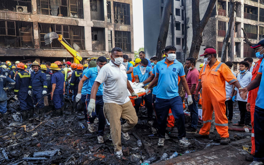 Rescue officials carry a victim's body at the site where Air India flight 171 crashed in a residential area near the airport in Ahmedabad on June 12, 2025. A London-bound passenger plane crashed in the Indian city of Ahmedabad on June 12 and all 242 people on board were believed killed, with the jet smashing into buildings housing doctors and their families. (Photo by Sam PANTHAKY / AFP)