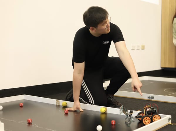 Kevin Guo points to small robot.