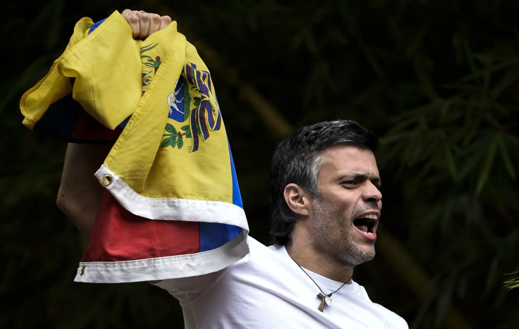 Leopoldo Lopez waves a Venezuelan flag on top of a wall outside his house in Caracas, hours after his release on Saturday 8 July 2017 (Venezuelan time).