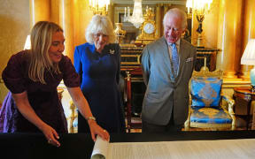 Britain's King Charles III and Britain's Queen Camilla are presented with the Coronation Roll, an official record of their Coronation, by the Clerk of the Crown in Chancery, at Buckingham Palace, central London on May 1, 2024. The Coronation Roll is the official State record of a monarch's accession and Coronation. The Roll contains details of The King’s accession, the planning of the Coronation, and a detailed description of the ceremony. (Photo by Victoria Jones / POOL / AFP)