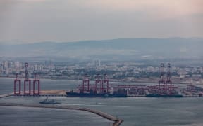Commercial ships and an Israeli naval vessel are seen in the port city of Haifa, Israel, along the coast of the Mediterranean Sea on December 21, 2023, after the United States announced its plans to establish a multinational coalition to protect cargo ships sailing through the Red Sea from attacks by Yemen's Iran-backed Houthi group. The group claims it is targeting ships heading for Israeli ports in response to Israel's assault on the Gaza Strip. (Photo by Mati Milstein/NurPhoto) (Photo by Mati Milstein / NurPhoto / NurPhoto via AFP)