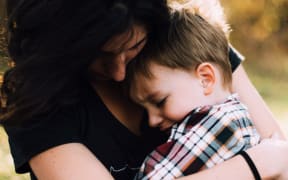 Mother holding child in arms.