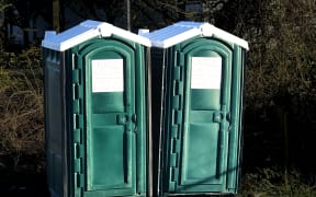 Two green portable toilets outdoors.