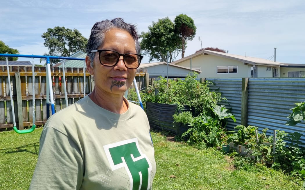 Project coordinator Rawinia Leatherby-Toia stands in front of a vegetable garden.