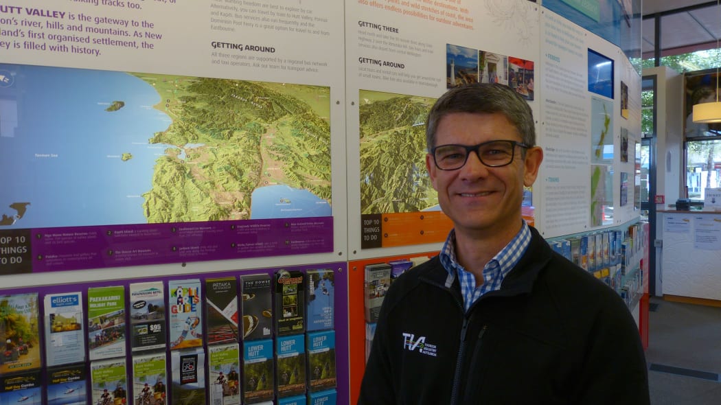 Chris Roberts the Chief Executive of Tourism Industry Aotearoa at the iSITE in Wellington. He is surrounded by New Zealand maps and tourist leaflets