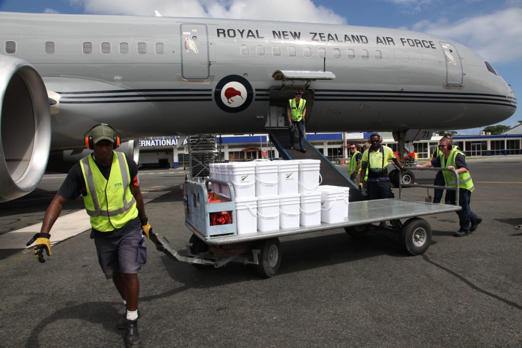A baggage handler at Bauerfield Airport, Port Vila, Vanuatu, pulls a trolley containing water containers from a Boeing 757 to a waiting RNZAF C130 Hercules. The Boeing arrived at Port Vila with 11 tonnes of relief supplies for Ambae Island.