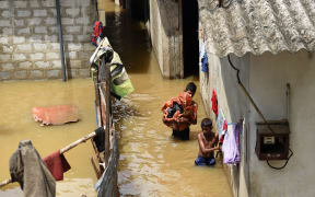 Sri Lankan youths wade through floodwaters as they go about their daily chores.