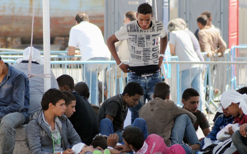 Migrants wait in Catania harbour after being recsued by the Italian coast guard.