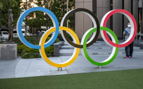 This picture taken on January 20, 2021 shows a visitor taking photos of the Olympic rings outside the Olympic Museum in Tokyo.