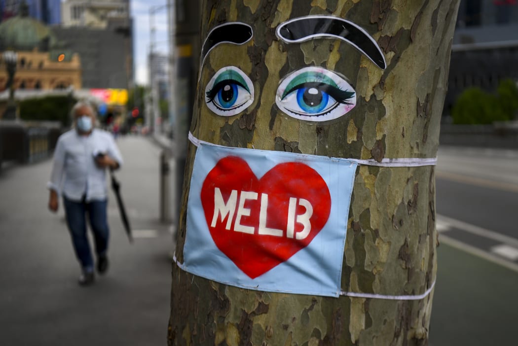 File photo: People walk past a tree decorated with eyes and a face mask in Melbourne's central business district  in October