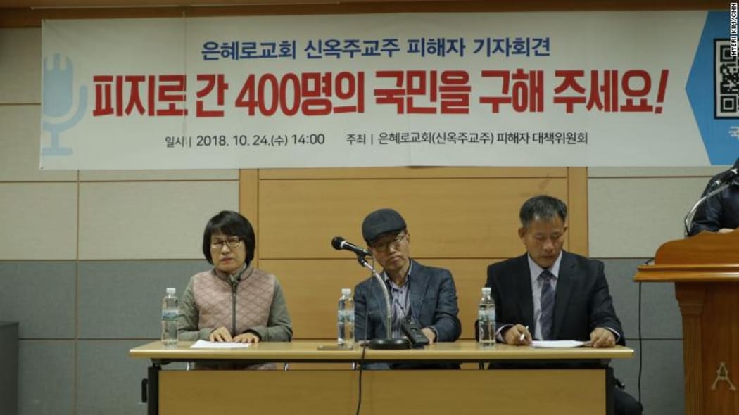 Former members of the Grace Road Church speak to the media. The banner above them reads "Please rescue 400 South Koreans in Fiji!"