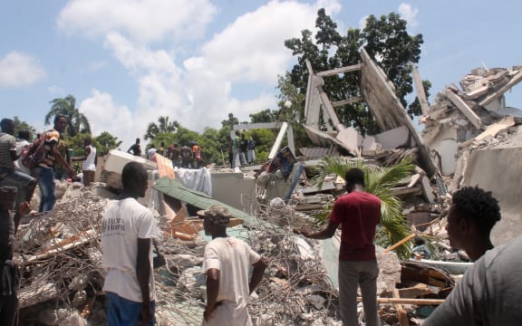 People search through the rubble of what used to be the Manguier Hotel after the earthquake hit on 14 August 
 2021 in Les Cayes, southwest Haiti.