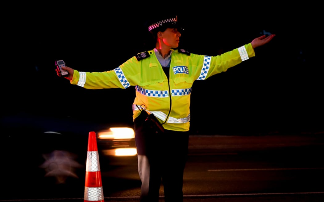 A police officer directing traffic at a alcohol check point.