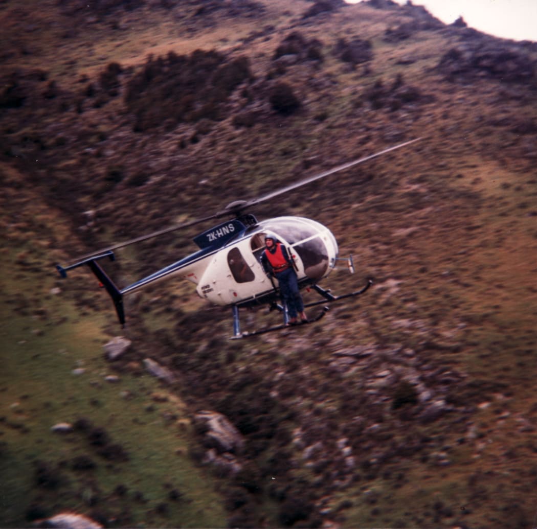 Man sitting outside of door of helicopter