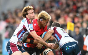 Christian Lio-Willie of the Crusaders is tackled by Tim Ryan of the Reds and Lawson Creighton of the Reds.