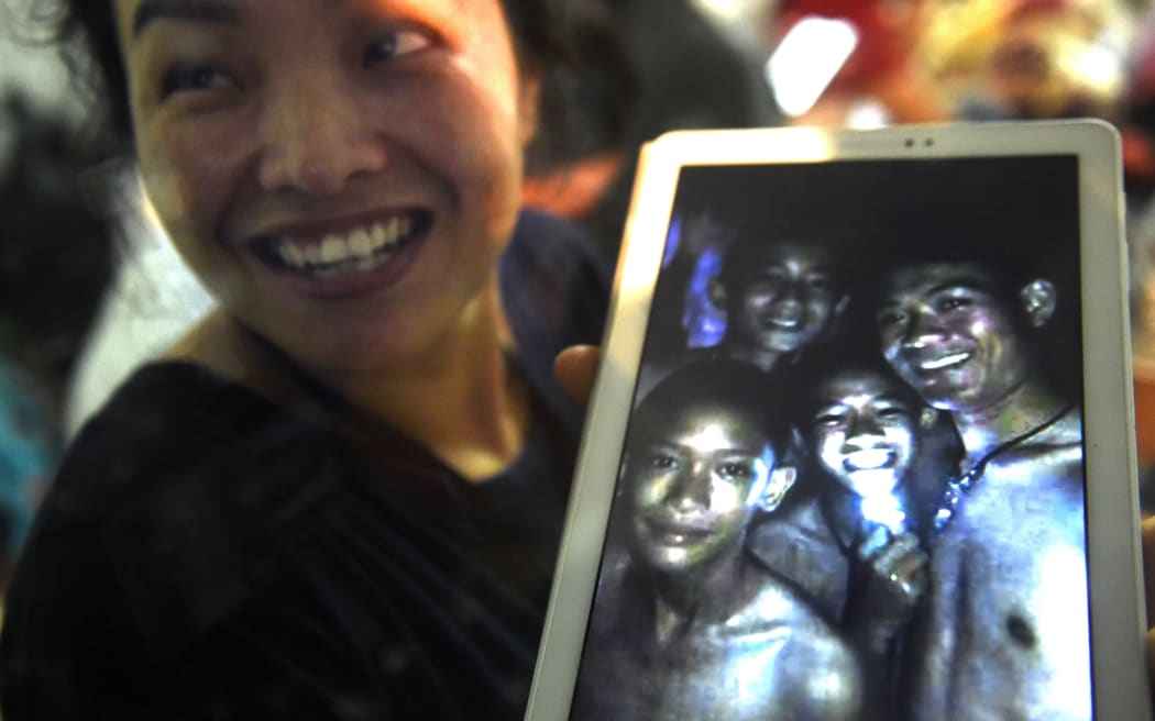 A happy family member shows the latest picture of the missing boys taken by rescue divers inside Tham Luang cave.