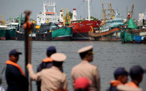 Navy officers prepare to inspect fishing boats lined up along the coast of Samut Sakhon, Thailand, to ensure they meet fishing industry standards. November 2015.
