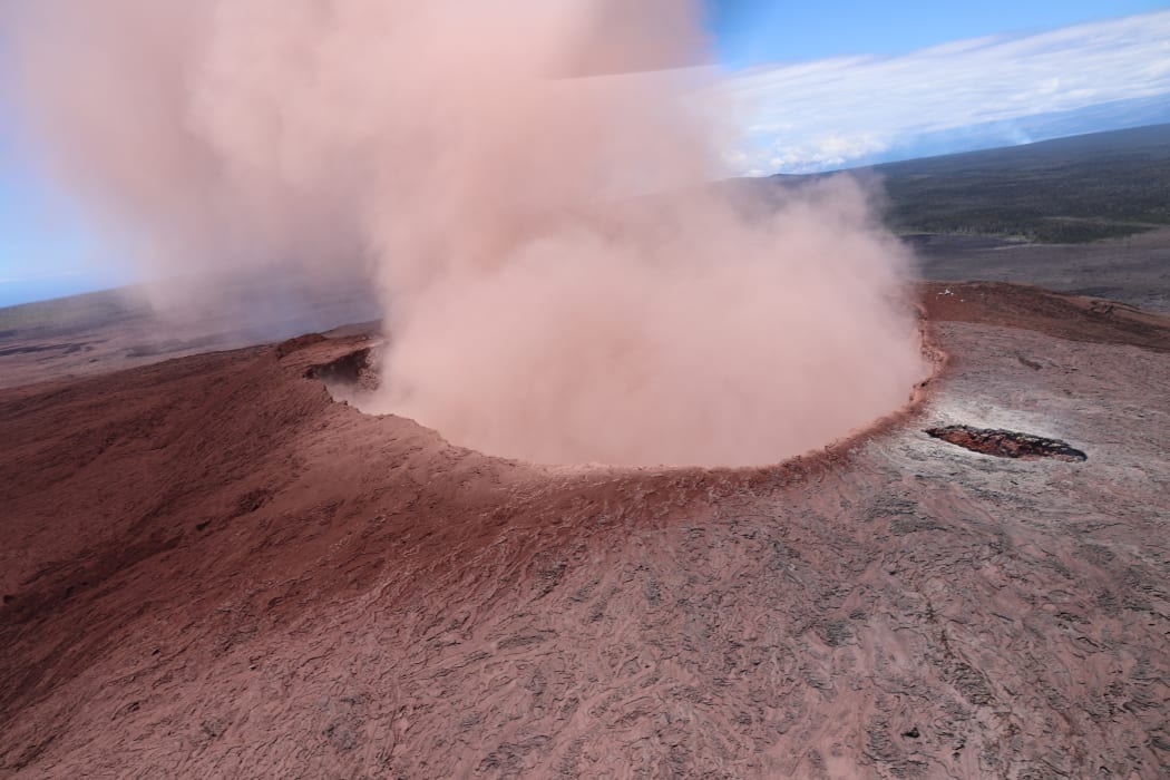 A view of Pu‘u ‘Ō‘ō from the east, shortly after a small collapse. The coating of red ash on the south side of the cone (left side of photo) is evident.