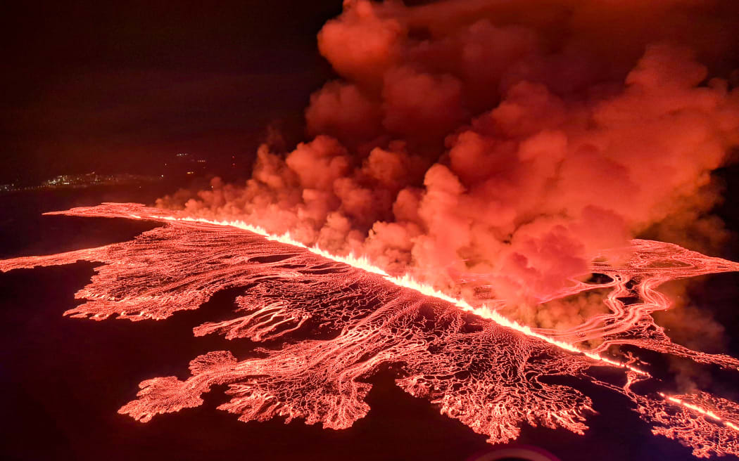 This handout picture released by the Icelandic Coast Guard on March 16, 2024 shows billowing smoke and flowing lava pouring out of a new fissure, during a surveilance flight above a new volcanic eruption on the outskirts of the evacuated town of Grindavik, western Iceland. A volcanic eruption started on the Reykjanes peninsula in southwestern Iceland on Thursday, the third to hit the area since December, authorities said. (Photo by HANDOUT / Icelandic Coast Guard / AFP) / RESTRICTED TO EDITORIAL USE - MANDATORY CREDIT "AFP PHOTO /HANDOUT/ICELANDIC COAST GUARD " - NO MARKETING - NO ADVERTISING CAMPAIGNS - DISTRIBUTED AS A SERVICE TO CLIENTS