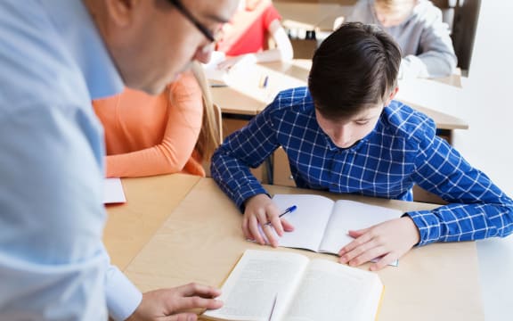 education, school, learning, teaching and people concept - group of students and teacher talking in classroom