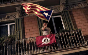 A man waves an 'Estelada' (Pro-independence Catalan flag) from a balcony after the closing of the 'Espai Jove La Fontana' (La Fontana youth center) polling station, on October 1, 2017 in Barcelona.