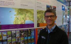 Chris Roberts the Chief Executive of Tourism Industry Aotearoa at the iSITE in Wellington. He is surrounded by New Zealand maps and tourist leaflets