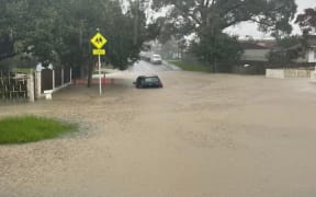 A car is caught in floodwaters on Kintara Drive, Massey, as downpours hit Auckland, 9 May 2023.