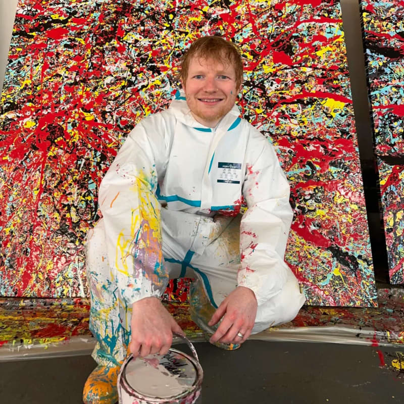 Ed Sheeran poses in front of his paintings created at an abandoned London car park.