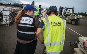 Aid workers and the Royal New Zealand Air Force personnel loading supplies