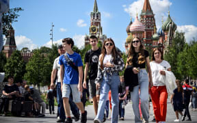 People walk in front of the Kremlin's Spasskaya tower (L) and St. Basil's cathedral in downtown Moscow, on July 23, 2024. (Photo by Alexander NEMENOV / AFP)