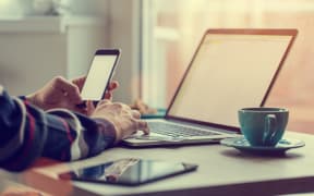 Man working on notebook, with a fresh cup of tea or coffee. Home work concept.